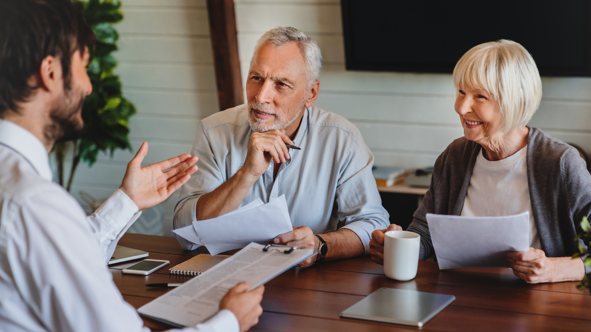 Senior couple meeting with male financial advisor or insurance agent at home